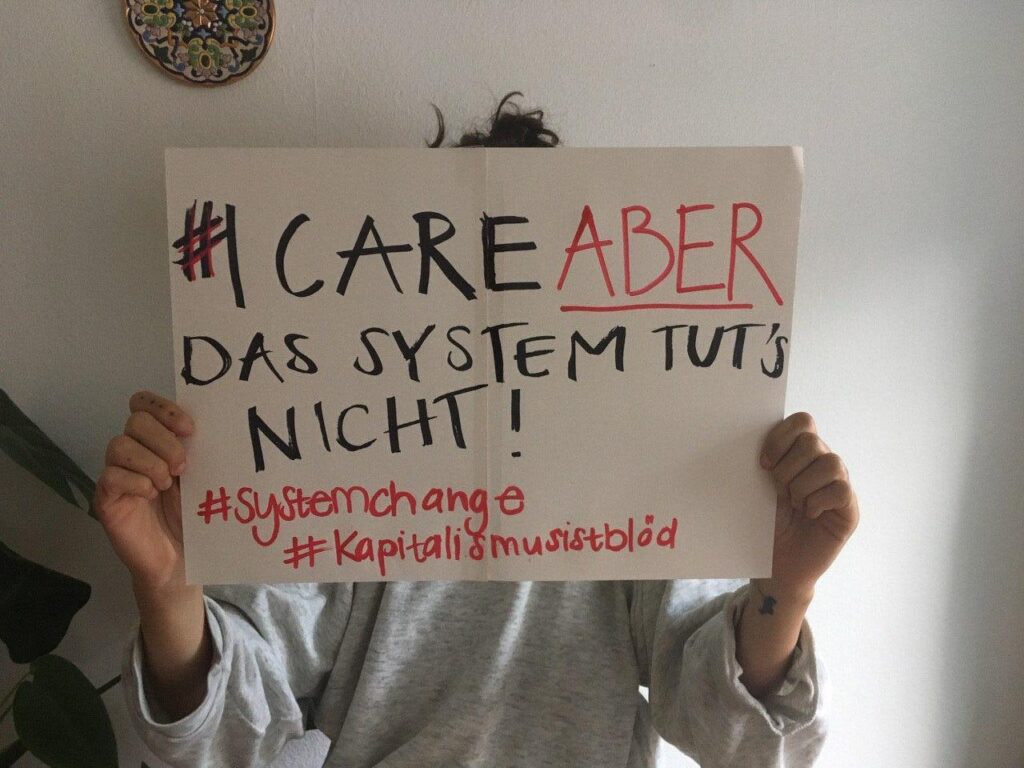 Aktivist*in hält Schild mit Aufschrift: #icareABER das System tut's nicht!