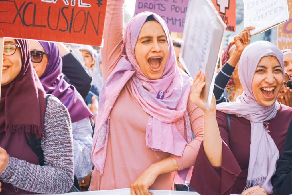 Drei Frauen mit lila und violettem Kopftuch an der 14.Juni 2019 Demonstration mit einem Transparent in der einen und jeweils Pancartas in der anderen hand, sie rufen kraftvoll