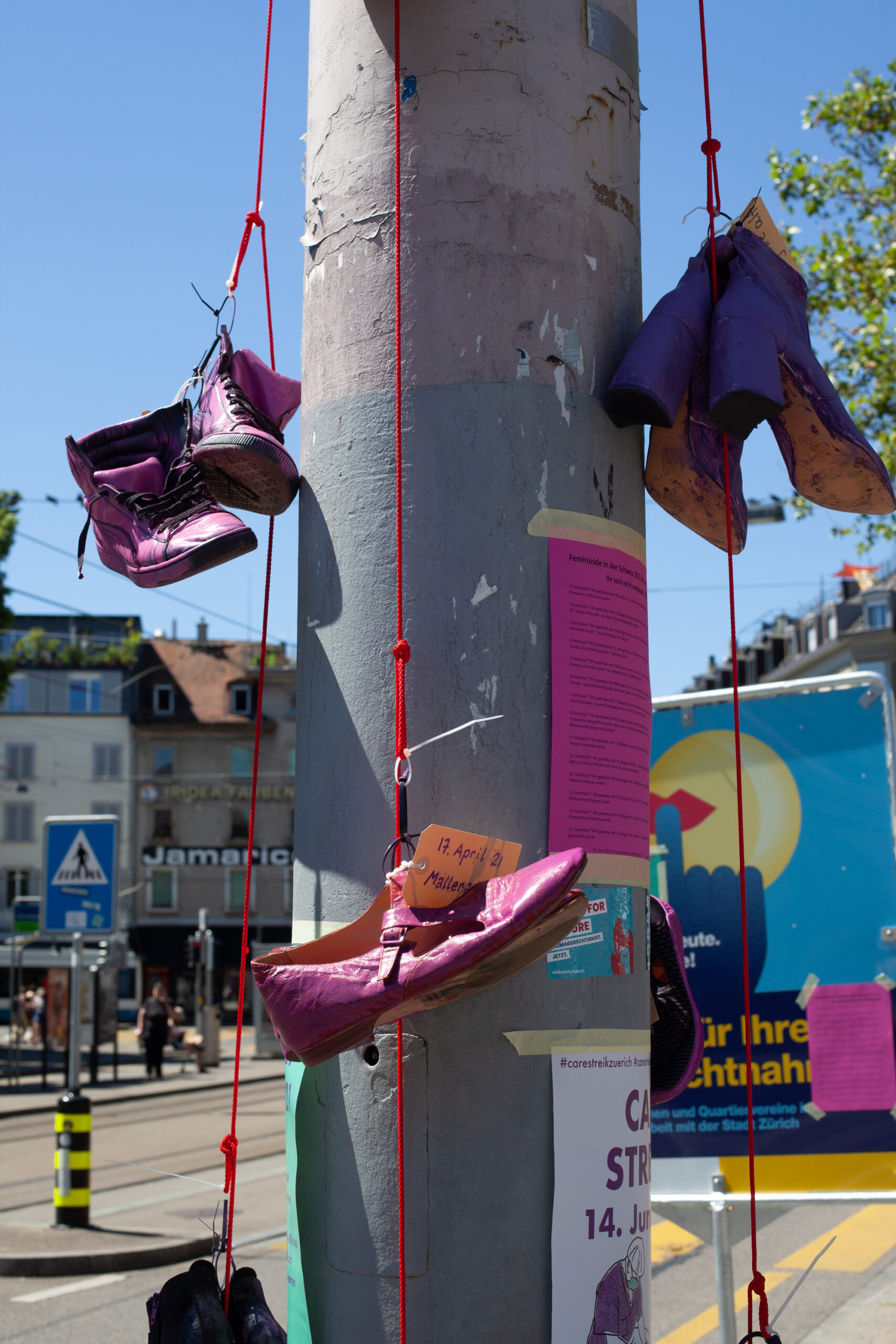 Schuhe, aufgehängt in Memoria an ermordete Frauen. Die Schuhe sind violett oder pink angemalt.